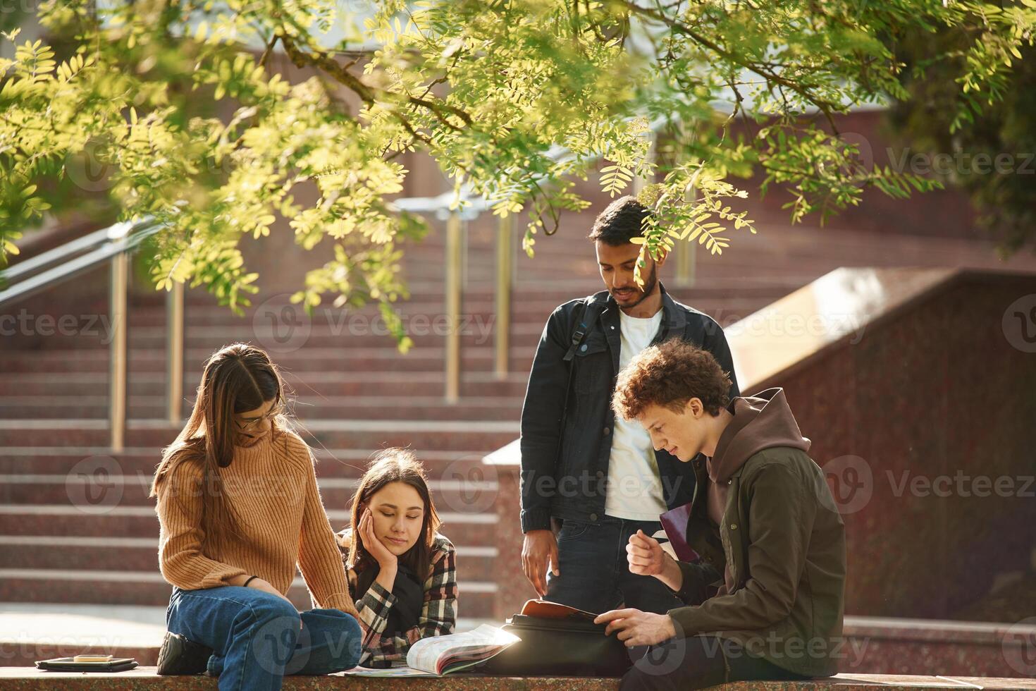 Hanging ,out after lessons. Four young students in casual clothes are together outdoors photo