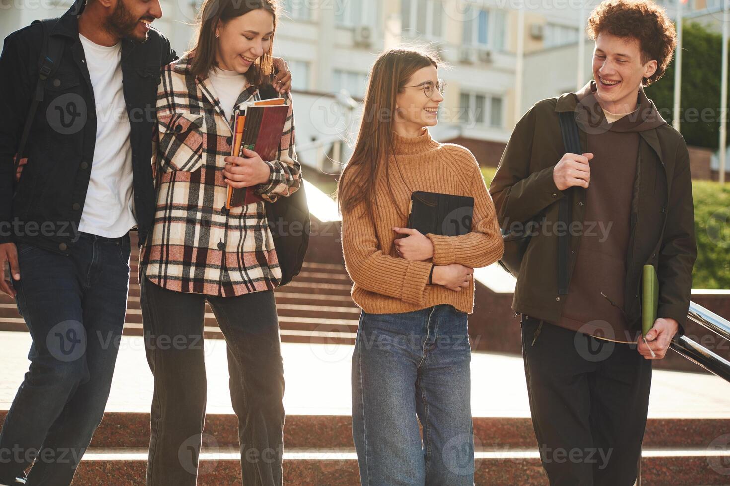 Front, view. .Four young students in, casual clothes are together outdoors photo