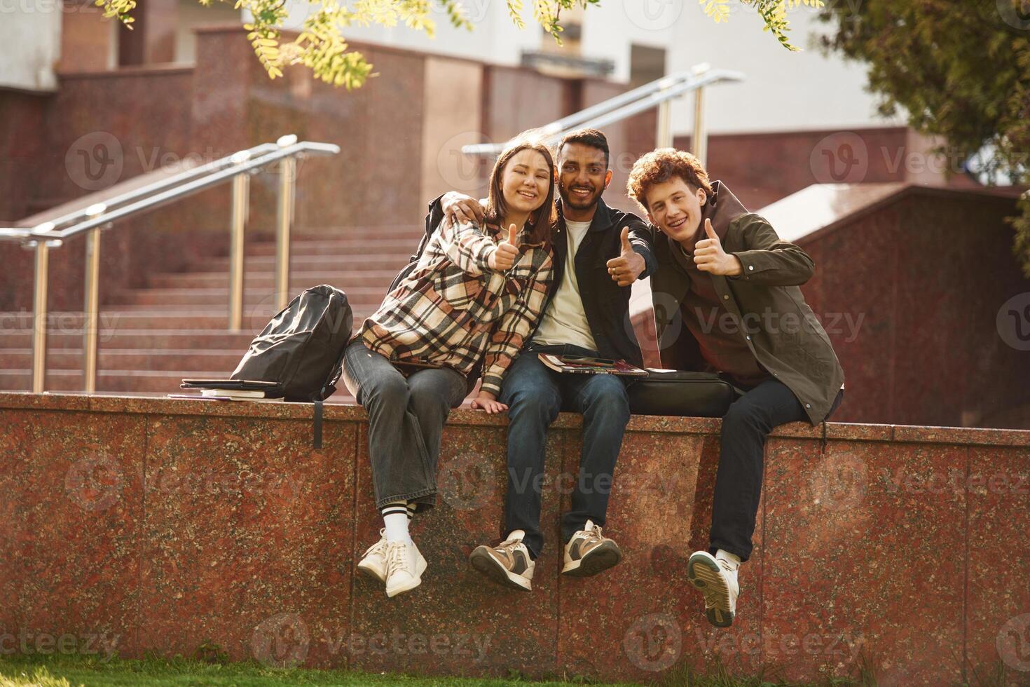 Three ,young ,students in casual clothes are together outdoors photo