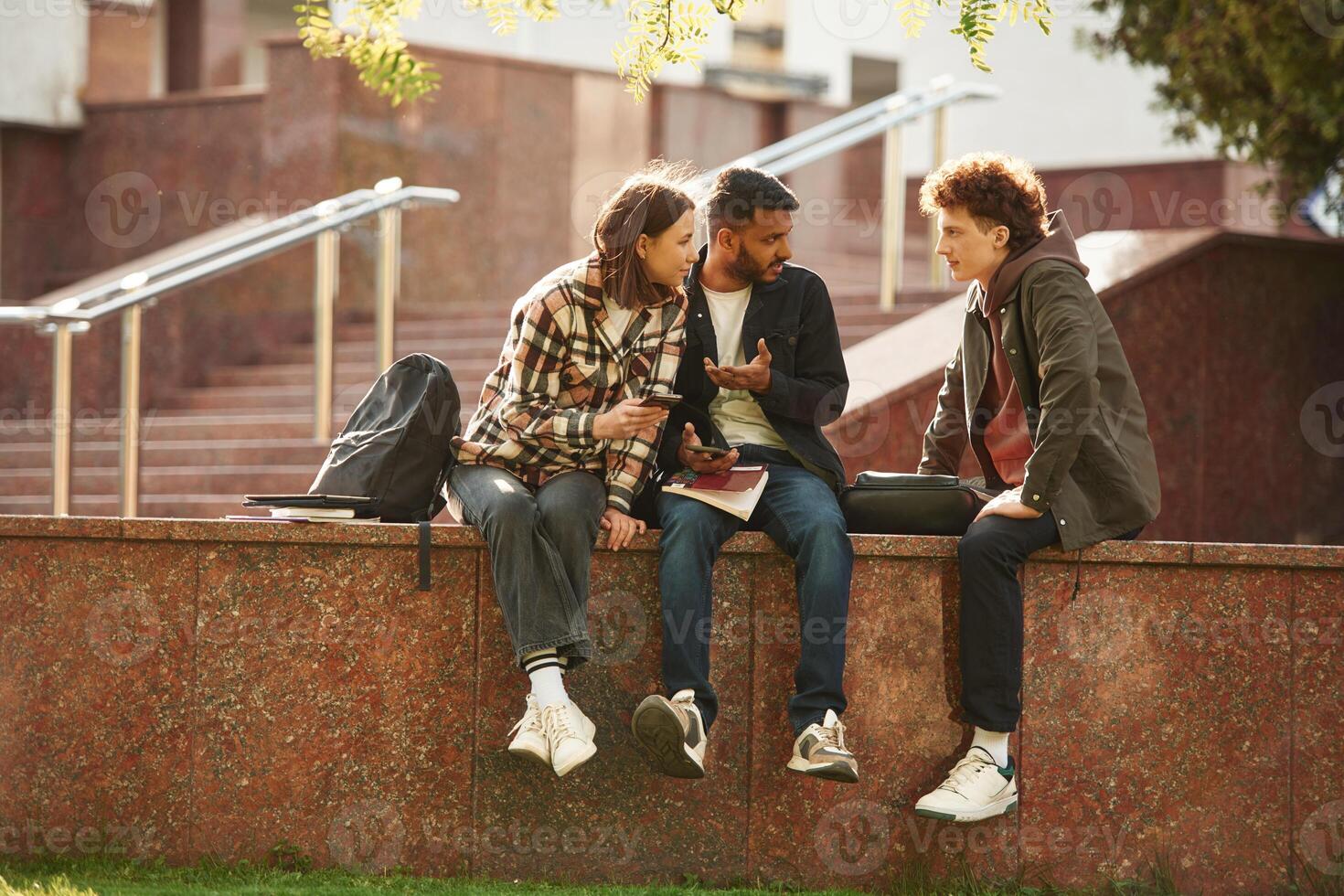 Three ,young students in casual clothes are together outdoors photo
