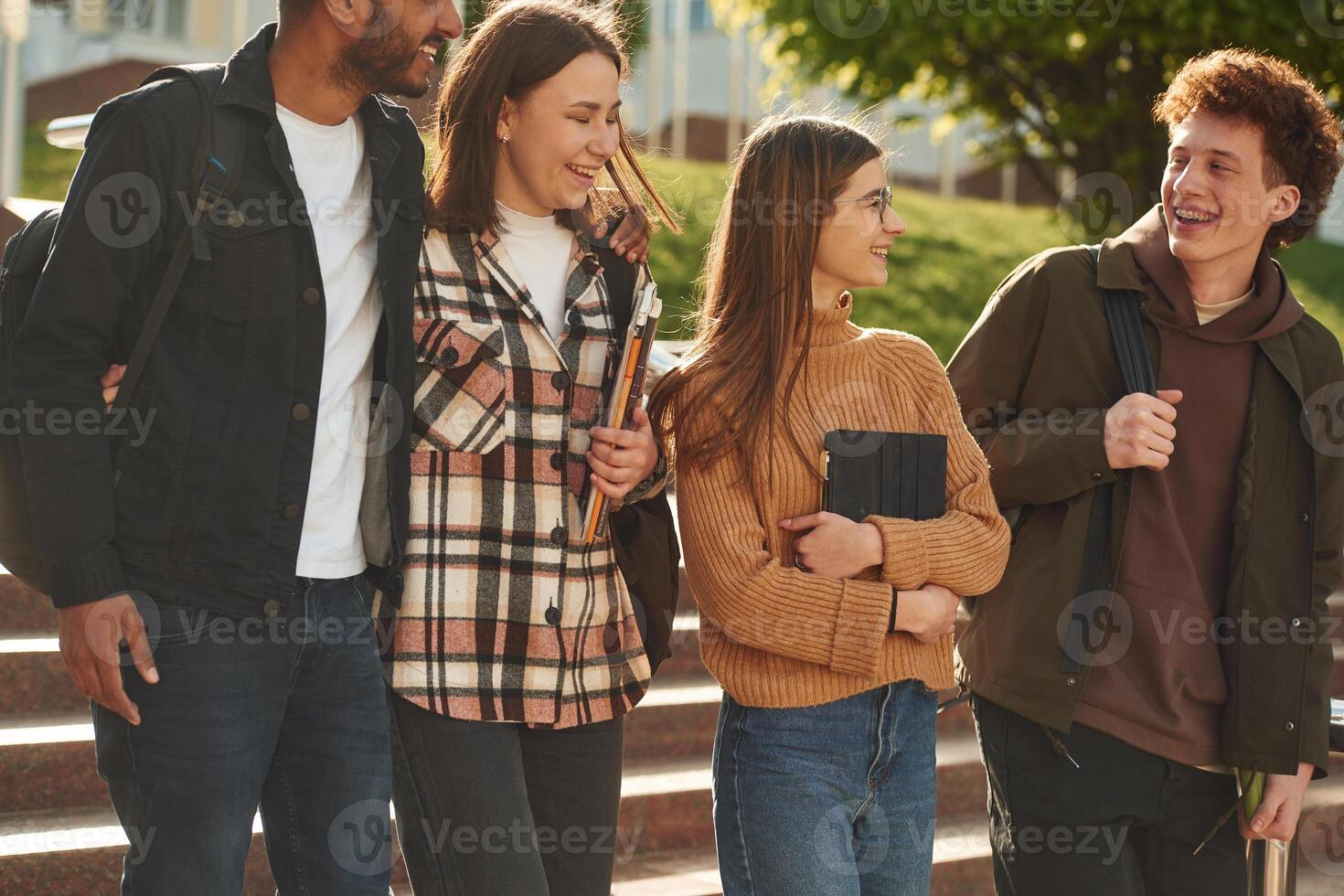 Front, view. Fou,r young ,students in casual clothes are together outdoors photo