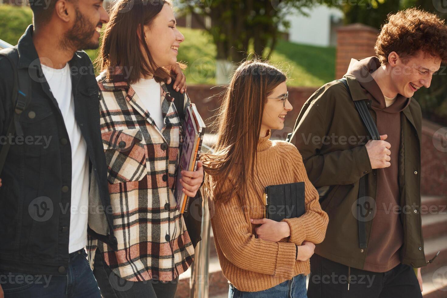 Four, young students in casual, clothes are together outdoors photo