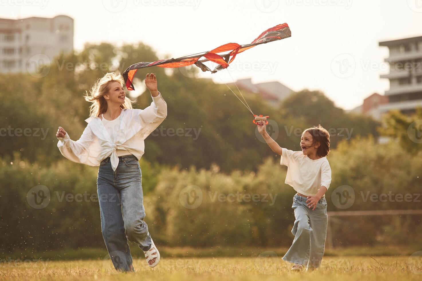 Playing with kite. Woman with her little daughter are on the summer field together photo