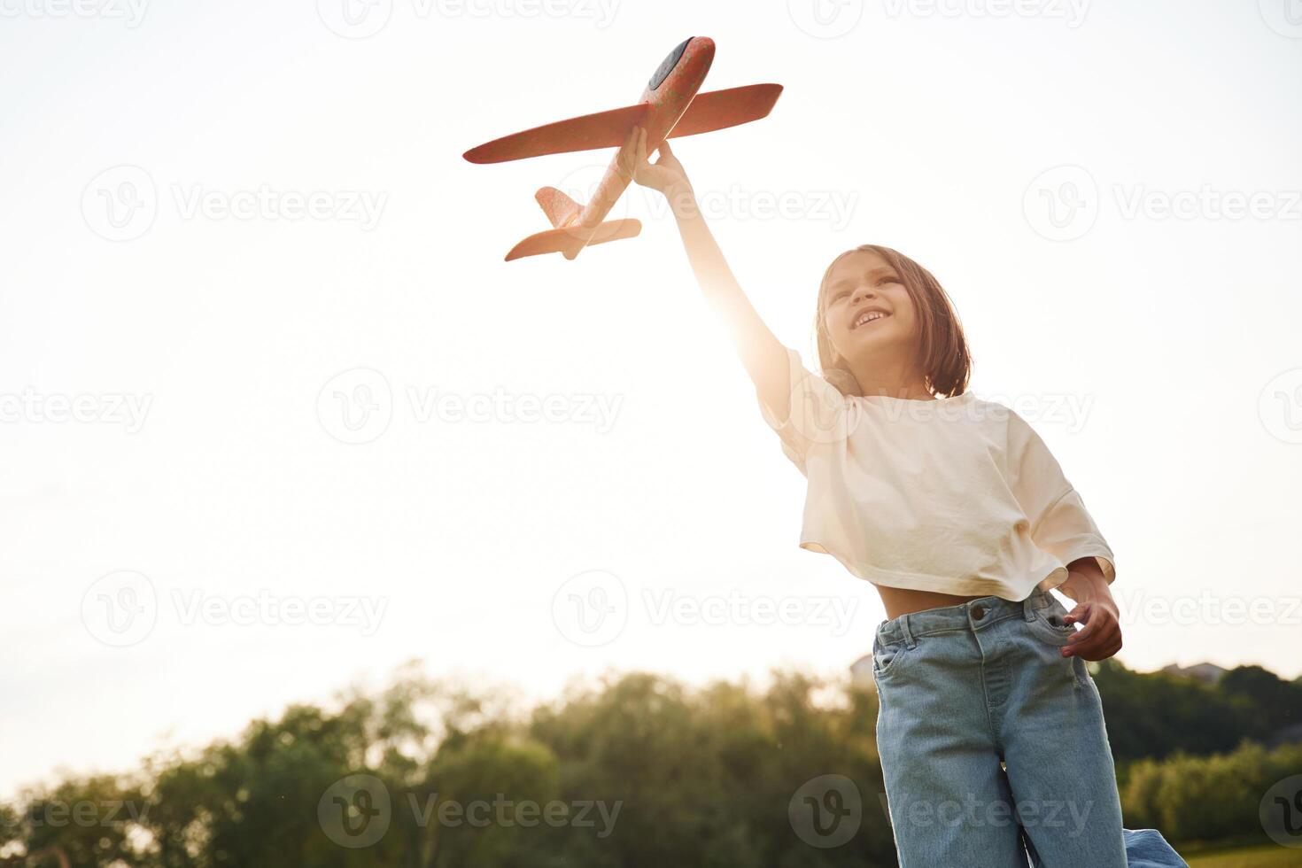 Front ,view. Happy ,little girl is playing with toy plane outdoors photo
