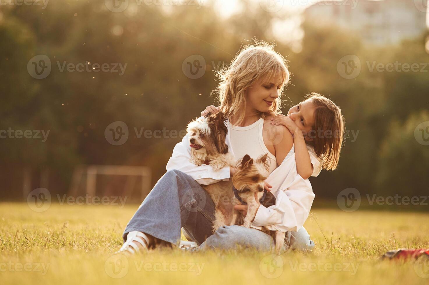 Embracing the, mother. Beautiful mother ,with her little daughter and dogs are on the summer field together photo