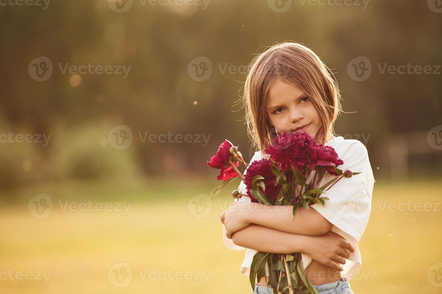 Holding ,beautiful ,red flowers. Little girl is on the summer field at daytime photo