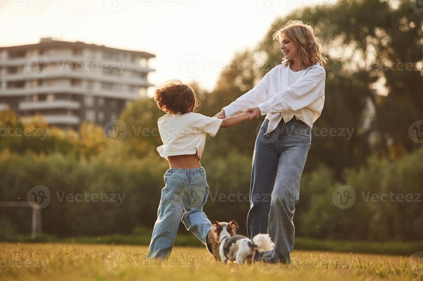 Beautiful mother with her little daughter and dog are on the summer field together photo