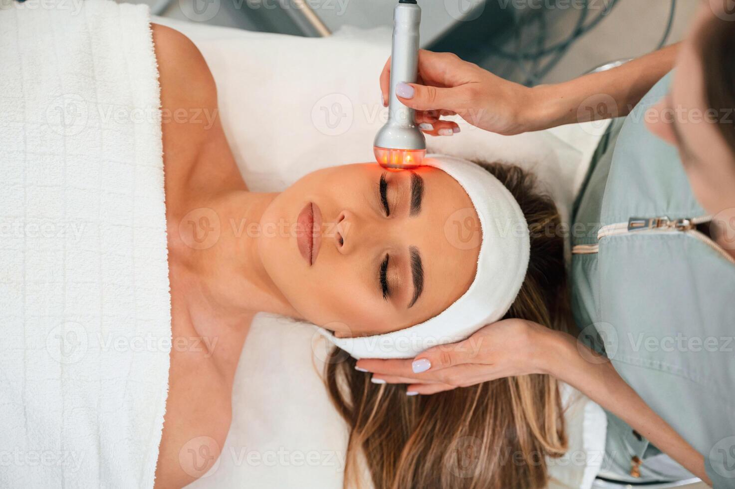 Electrical therapy tool. Woman face getting facial care by beautician hands at spa salon photo
