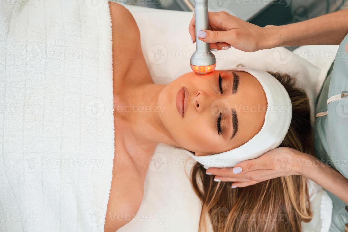 Apparatus for galvanization is used.. Woman face getting facial care by beautician hands at spa salon photo