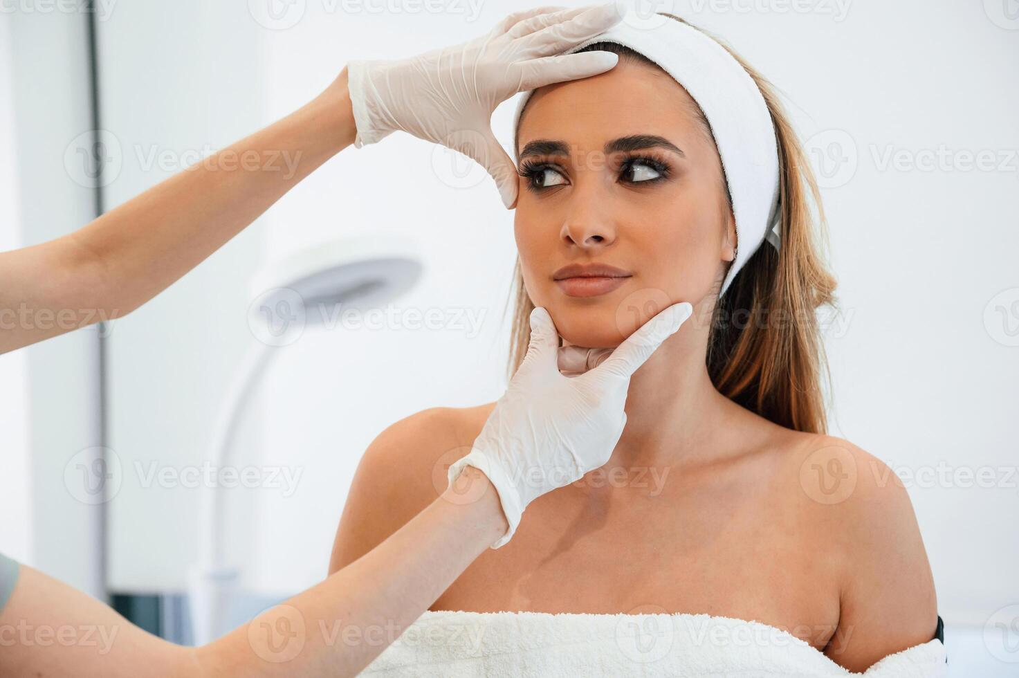 Checking, final results. Woman face getting facial care by beautician at spa salon photo