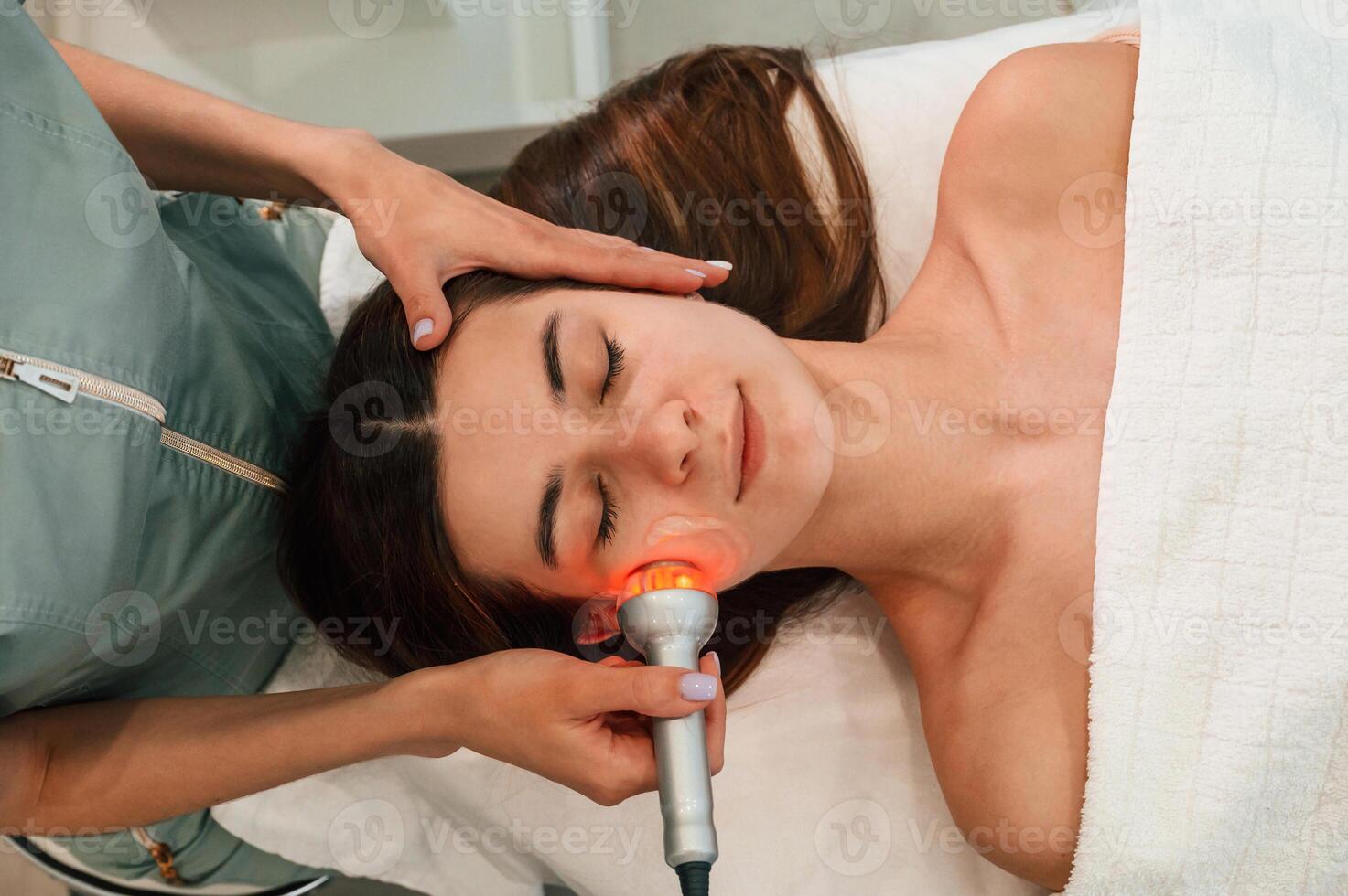 Electrical therapy, tool. Woman face getting facial care by beautician hands at spa salon photo