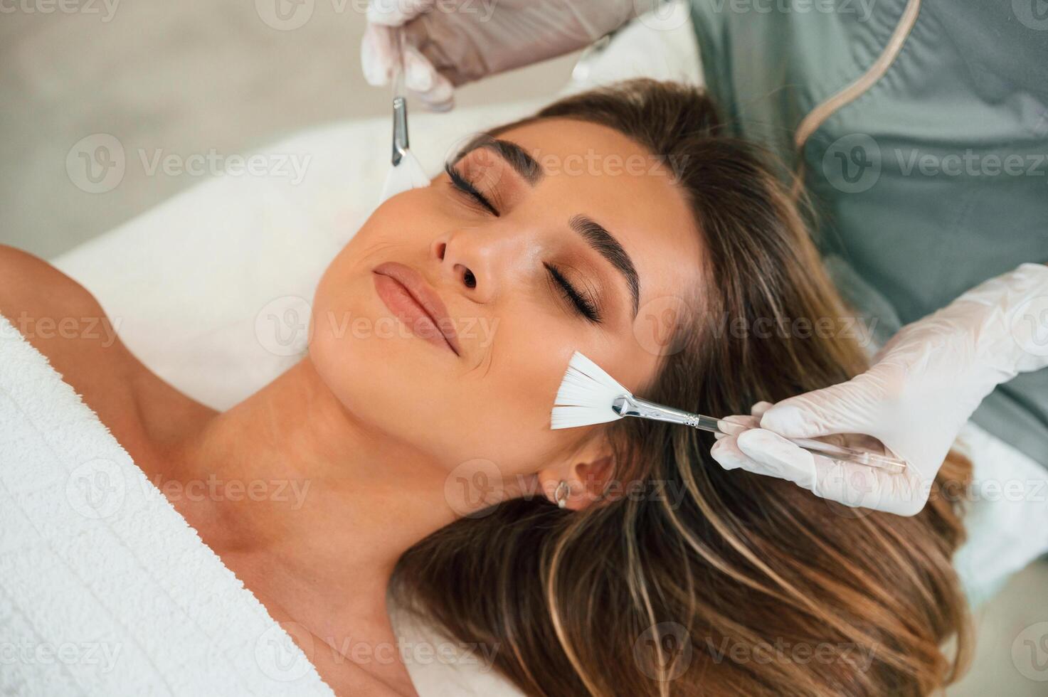 Cleaning, skin,by brushes. Woman face getting facial care by beautician hands at spa salon photo