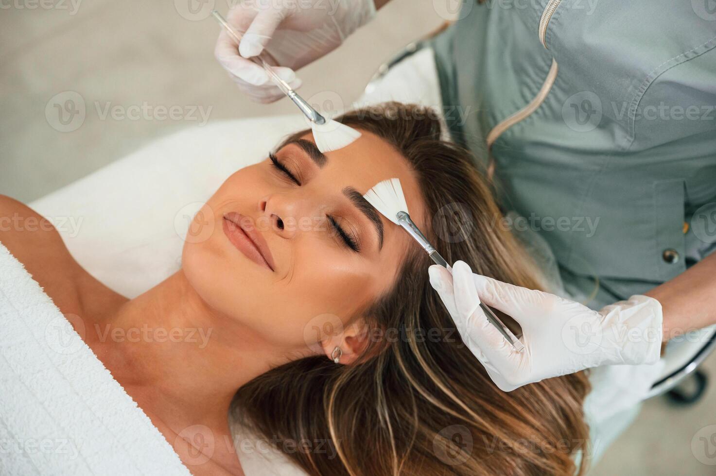 Cleaning, skin by ,brushes. Woman face getting facial care by beautician hands at spa salon photo