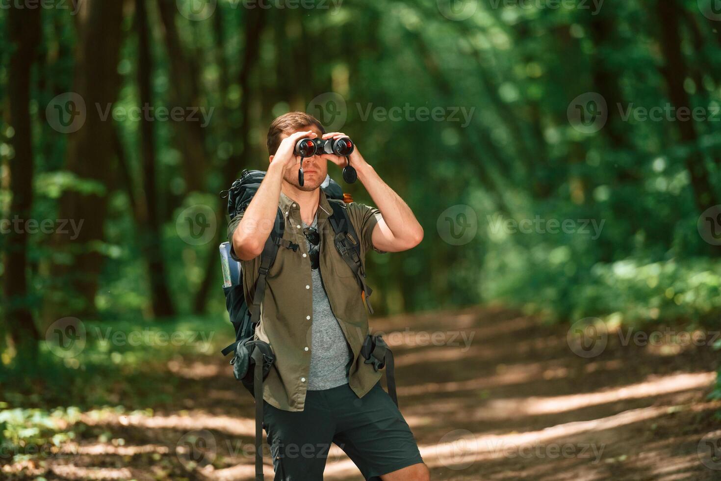 Looking ,through the, binoculars. Tourist in summer forest. Conception of exploration and leisure photo