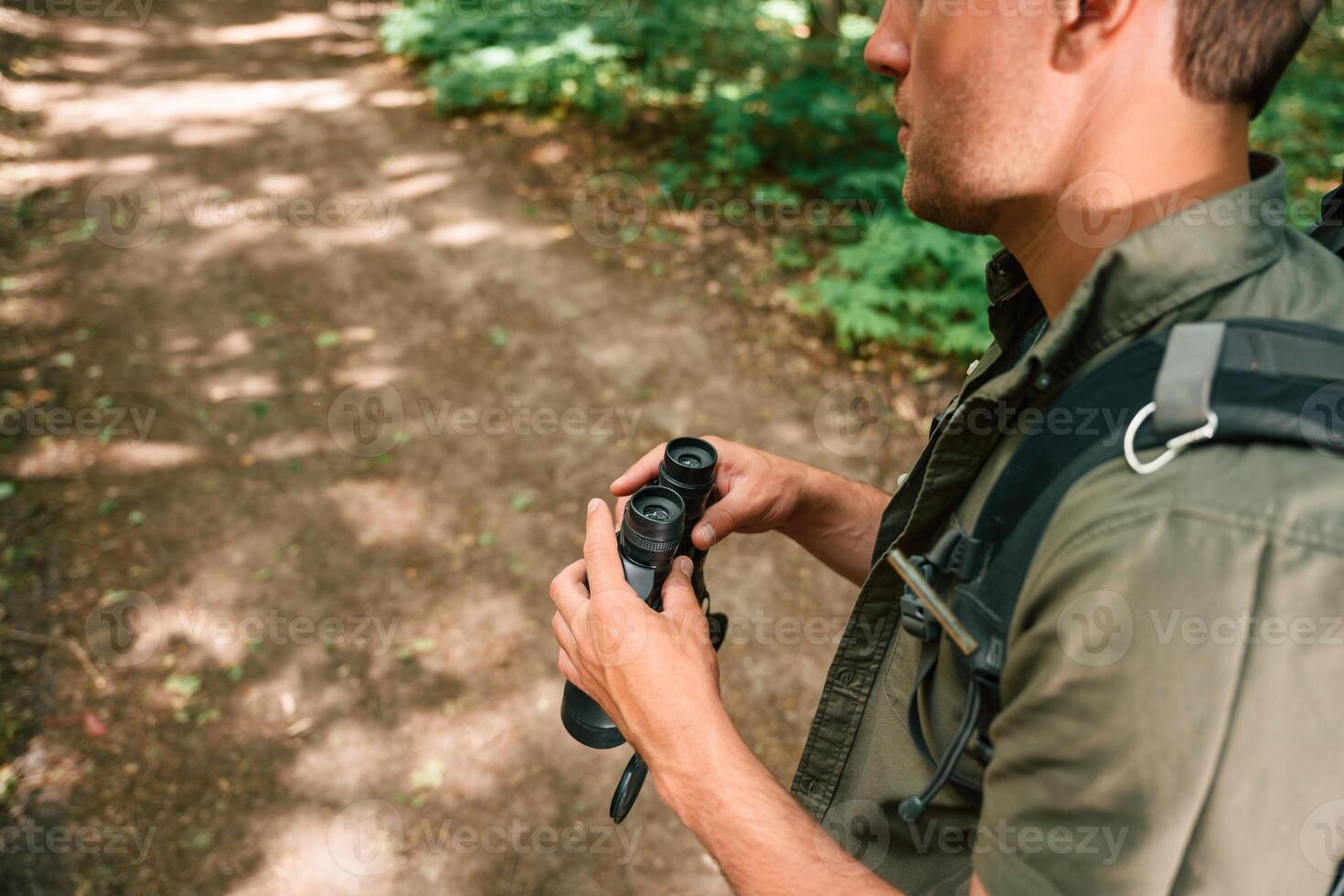 Looking for the way. Holding binoculars. Tourist in summer forest. Conception of exploration and leisure photo