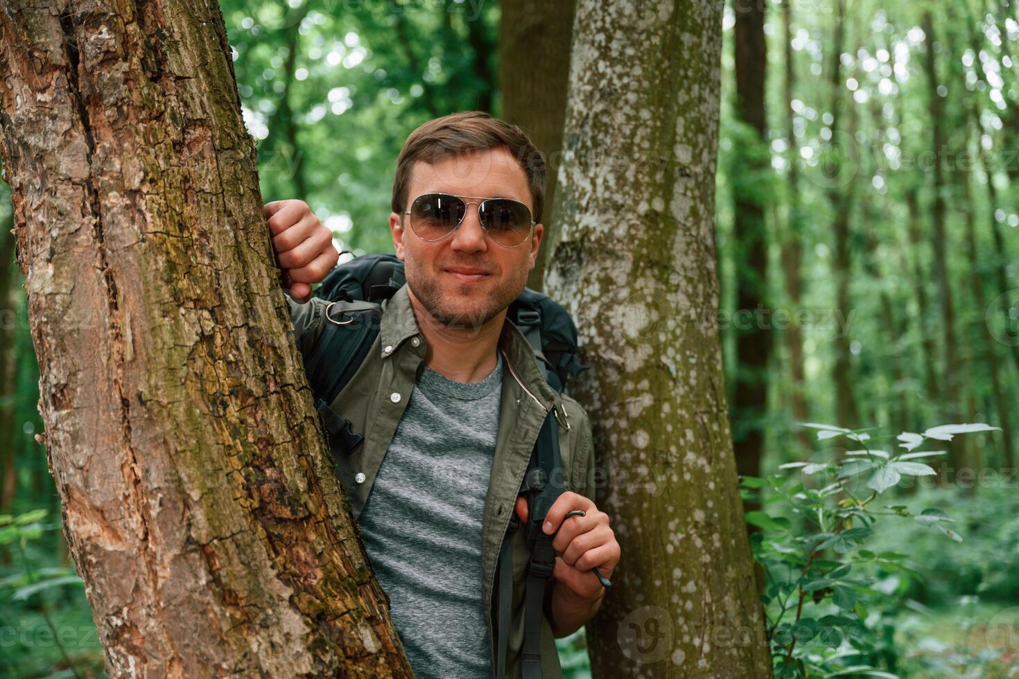 Standing ,between the trees. Tourist in summer forest. Conception of exploration and leisure photo