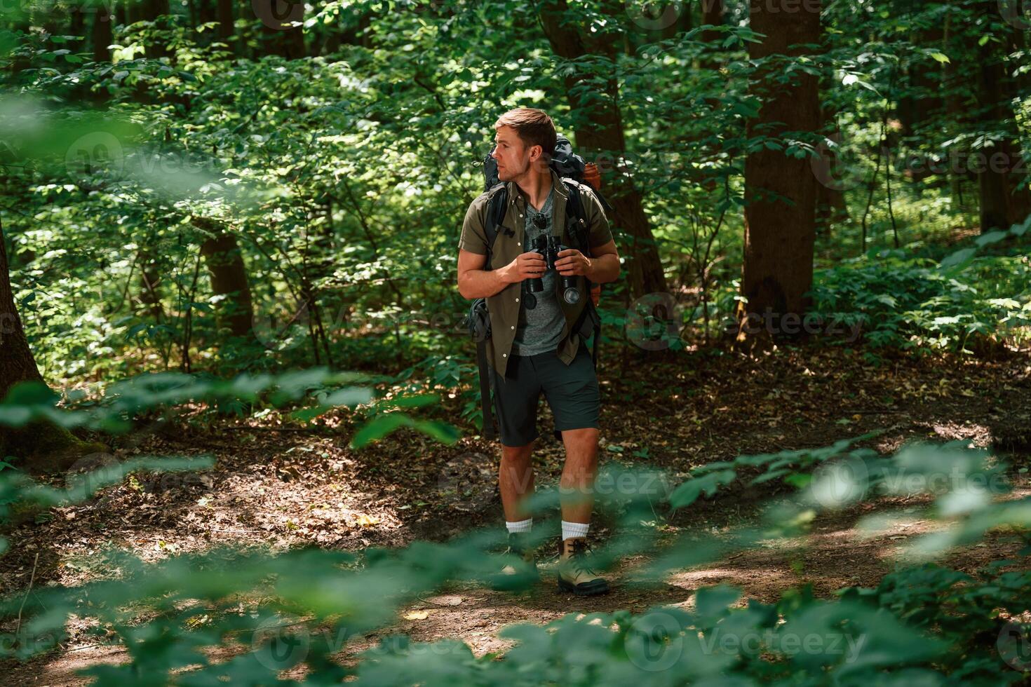 Looking ,for the way. Holding binoculars. Tourist in summer forest. Conception of exploration and leisure photo