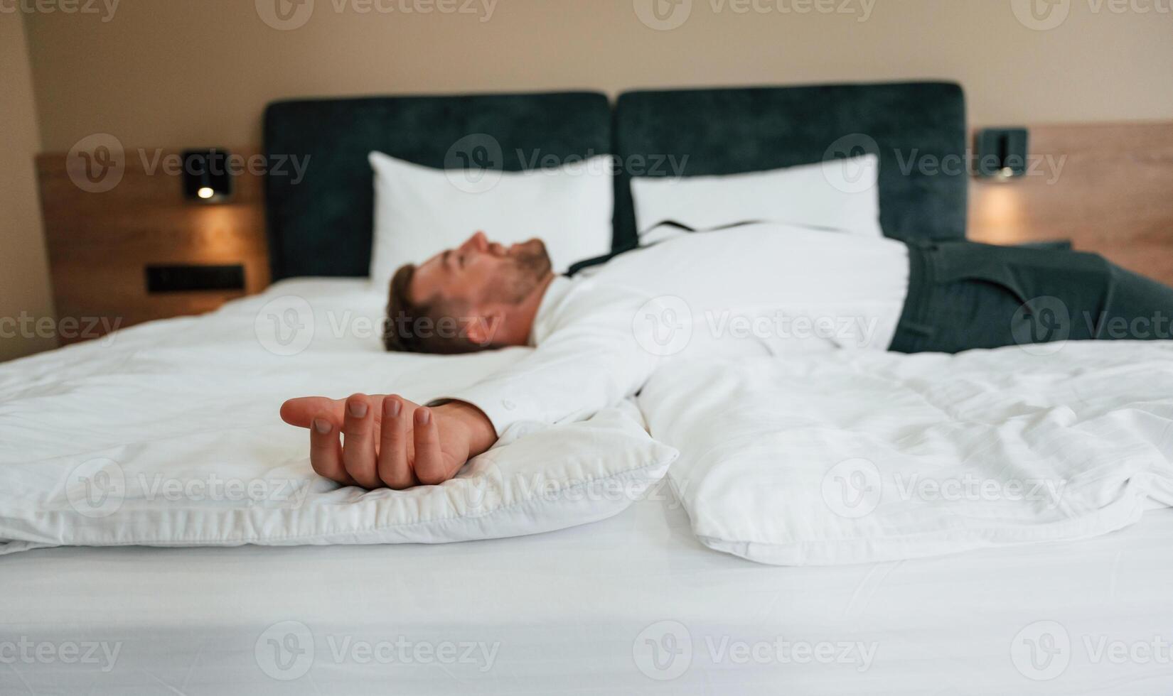Tired, lying down ,on ,the bed. Businessman is indoors in the hotel room photo