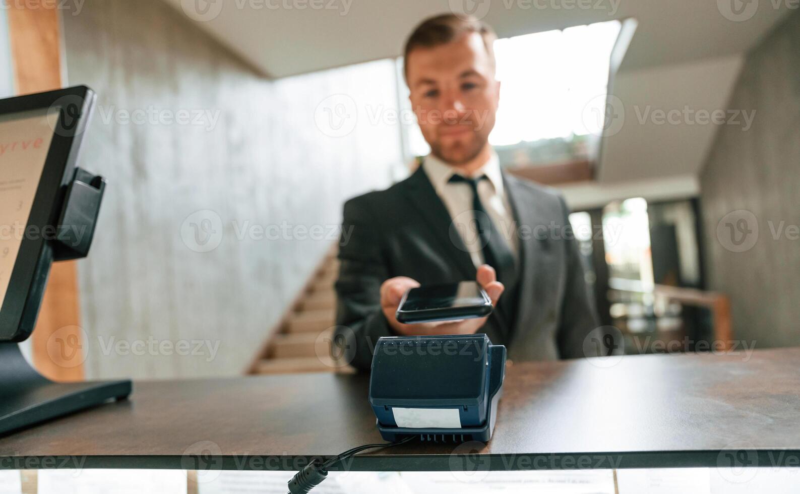 Making ,payment, by using phone and terminal. A man in a black jacket at the hotel reception photo