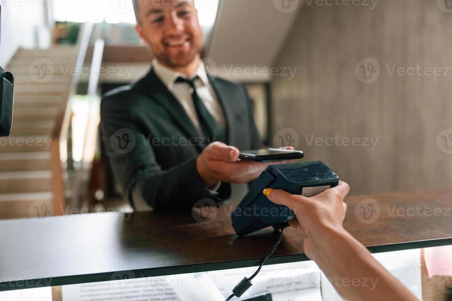 Wireless payment by using ,phone and t,erminal. A man in a black jacket at the hotel reception photo