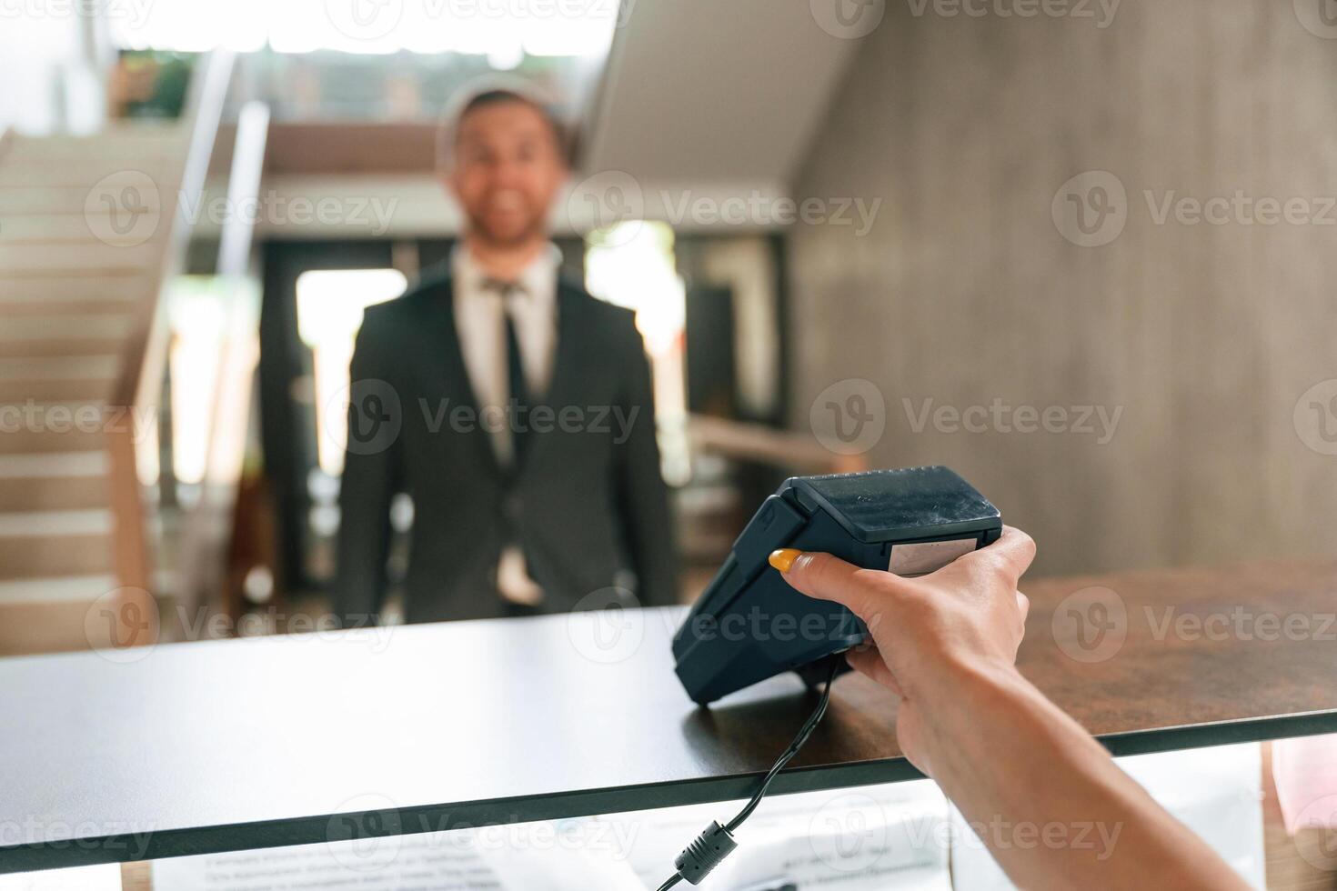 Making payment by using phone and t,erminal. A man in a black jacket at the hotel reception photo