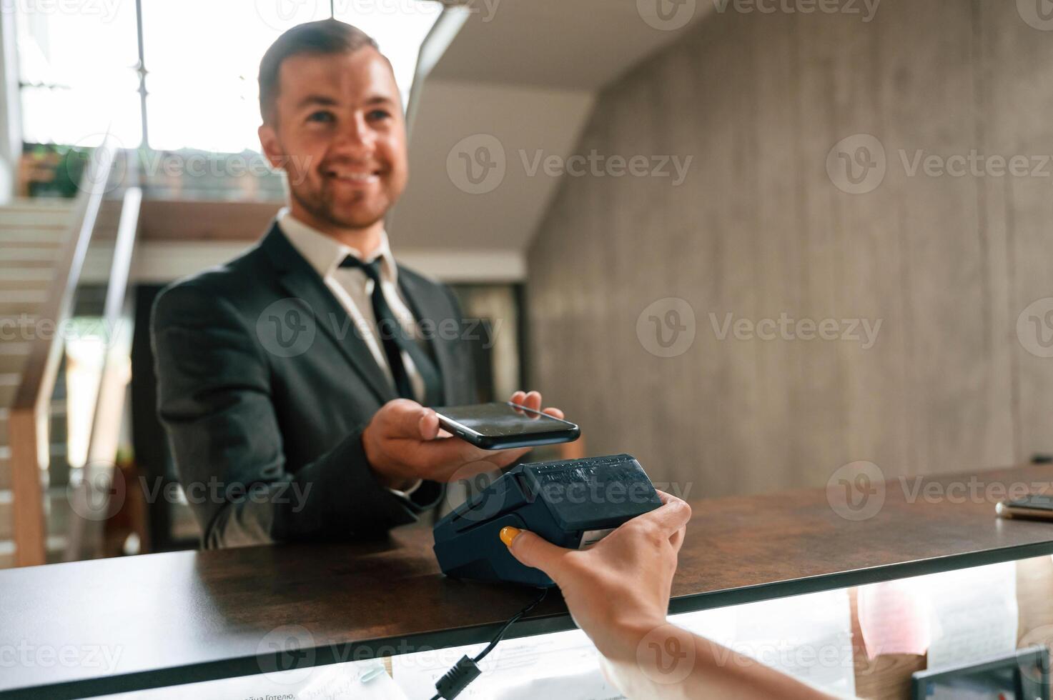 Making ,payment by using phone ,and terminal. A man in a black jacket at the hotel reception photo