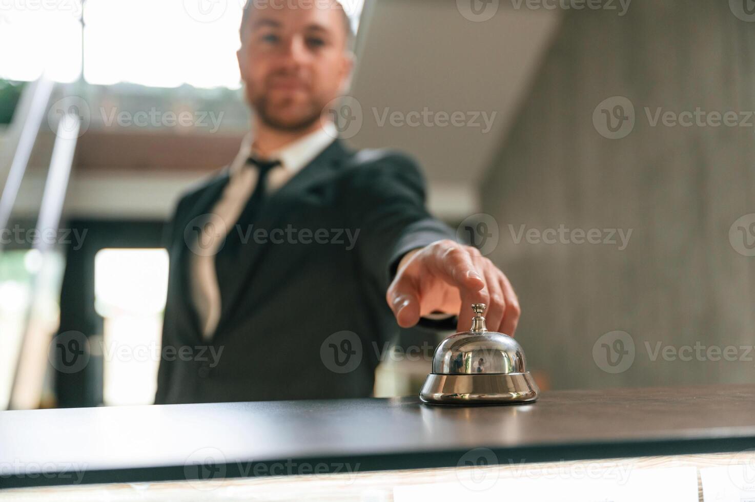 Standing, using hotel ,desk bell.. A man in a black jacket at the hotel reception photo
