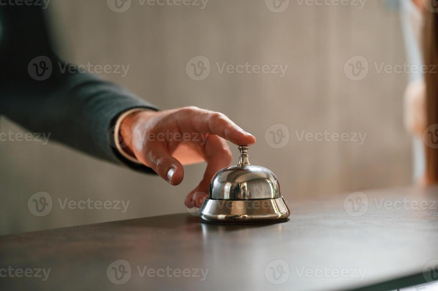 Close up view, using hotel desk bell.. A man in a black jacket at the hotel reception photo