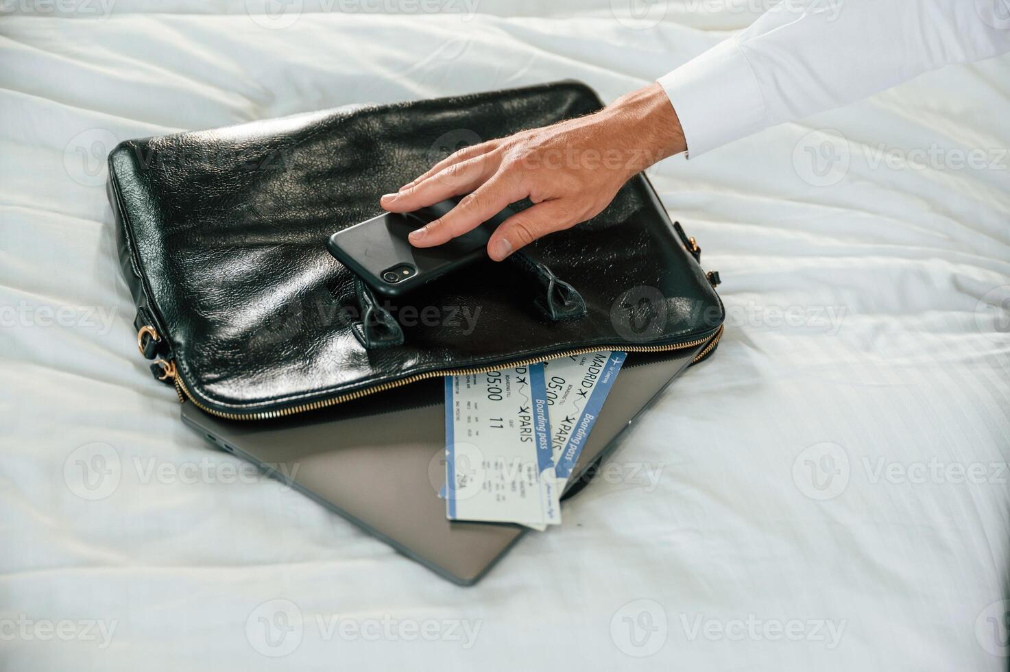 Close up view, of businessman that is sitting on bed with tickets for travel on it photo