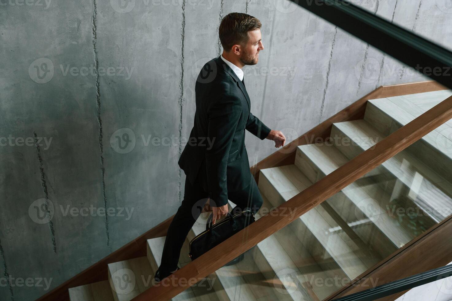 Walking up... Man, in business suit and tie with case in hands is on the stairs photo