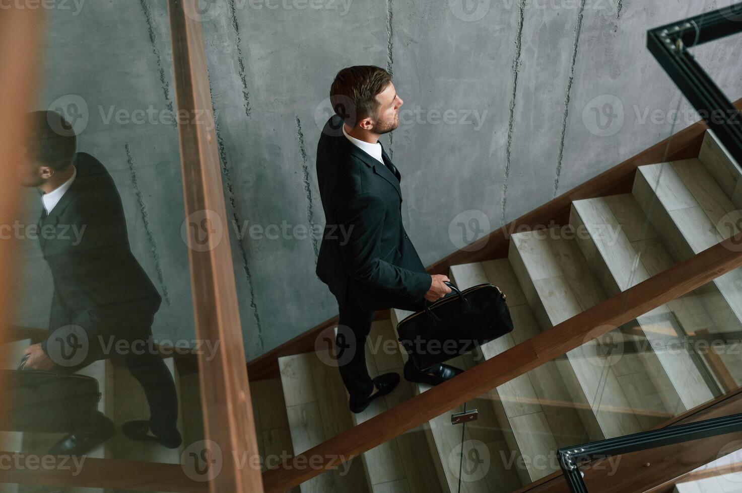 Walking ,up... Man in business suit and tie with case in hands is on the stairs photo