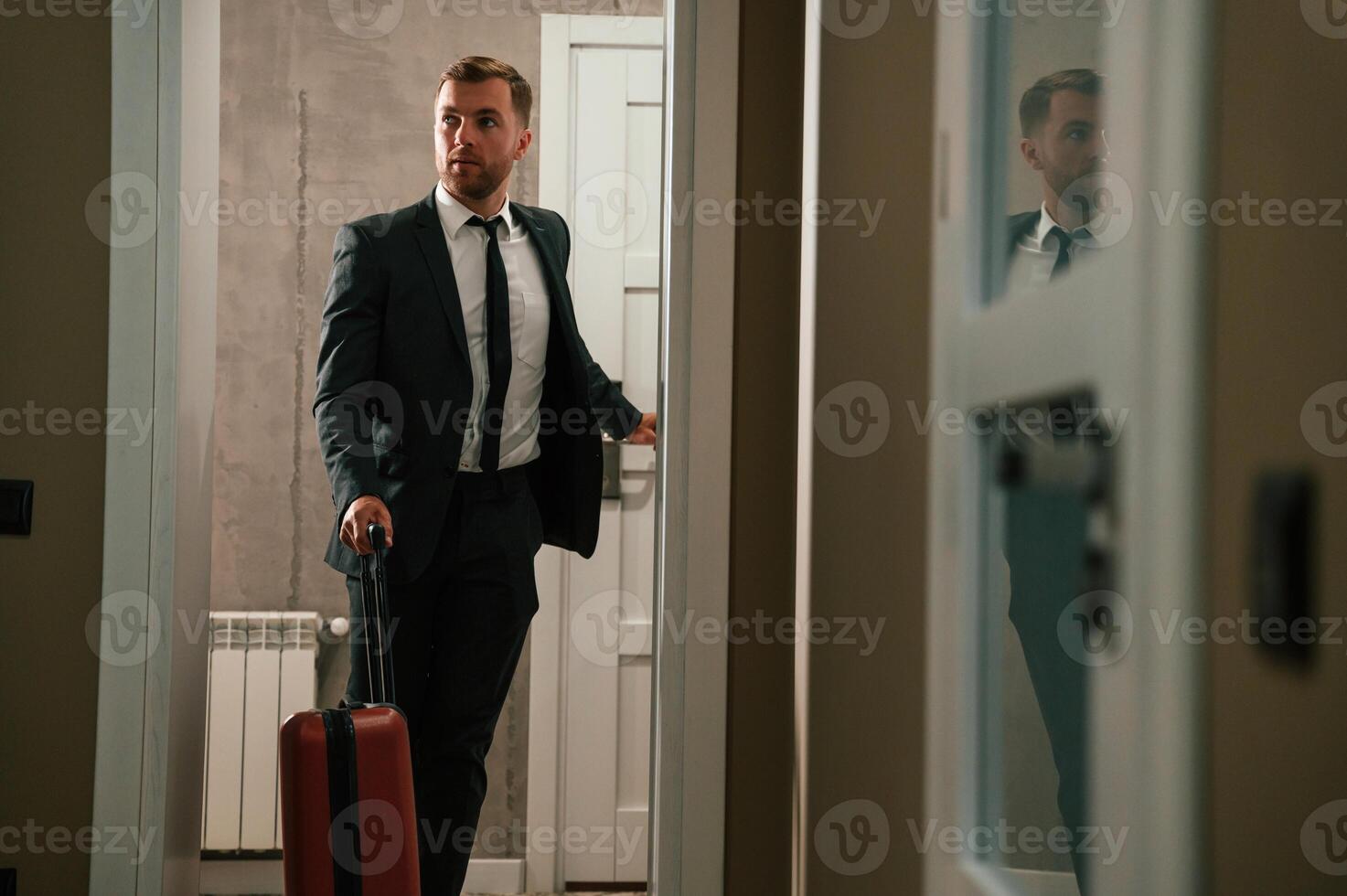 Entering ,the appartment and and holds a suitcase in his hands. Handsome businessman is indoors in the hotel room photo