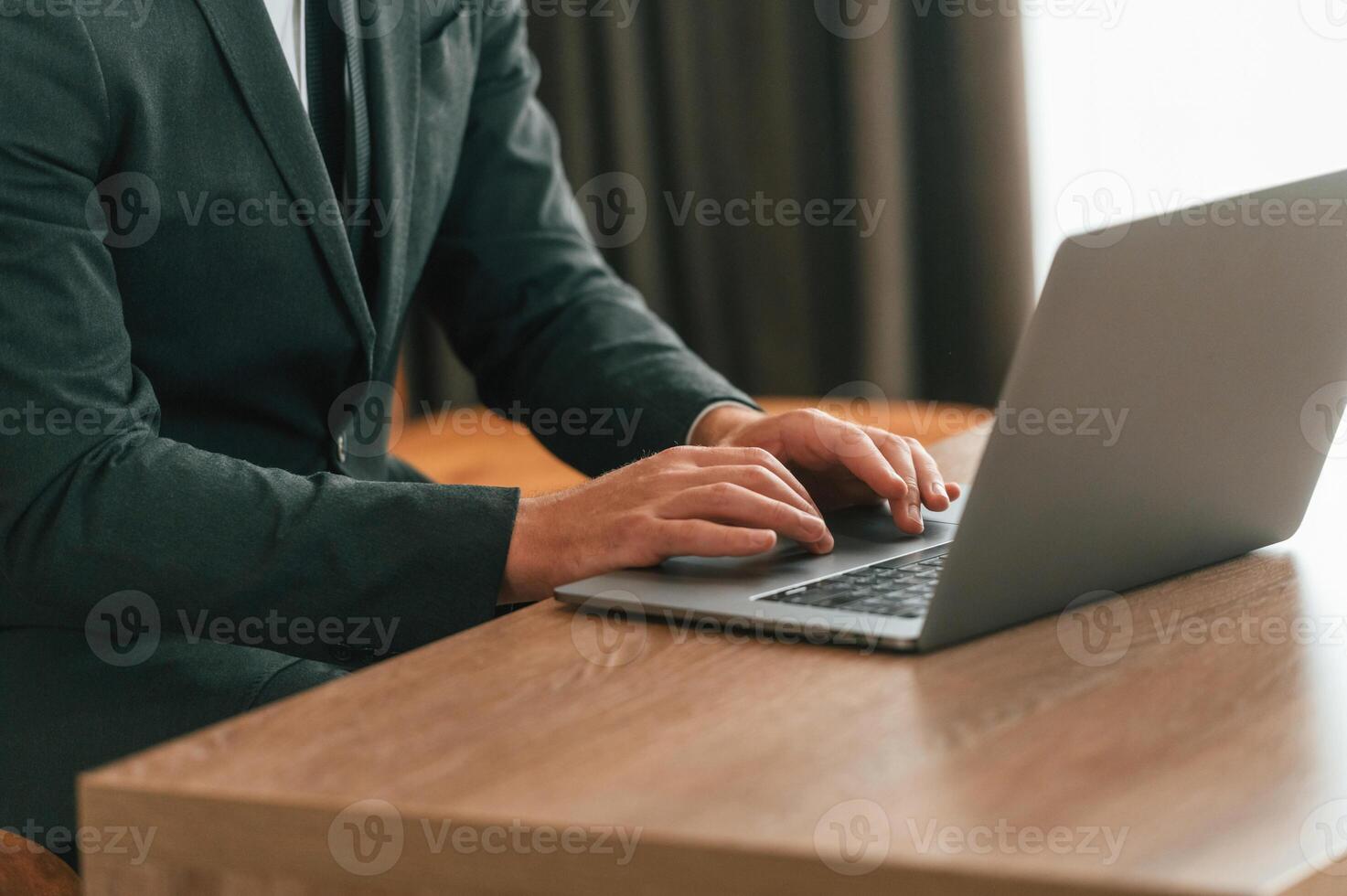 Close up view of businessman in suit and tie that is working by using laptop photo