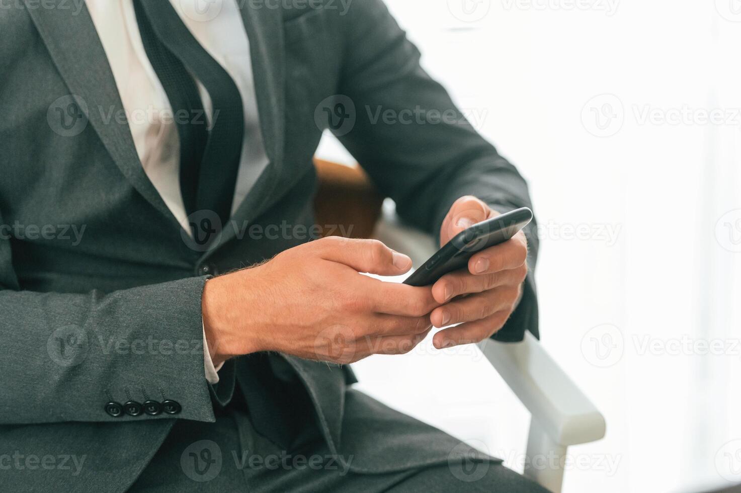 Close up view ,of businessman that is sitting and using smartphone photo