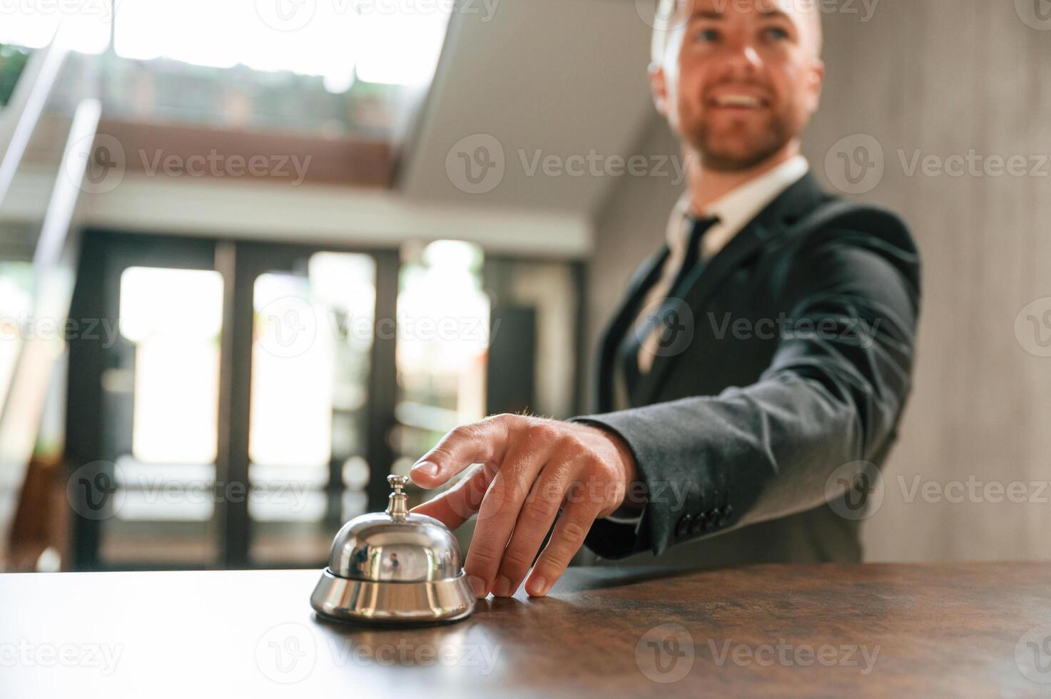 Standing, using ,hotel desk bell. A man in a black jacket at the hotel reception photo