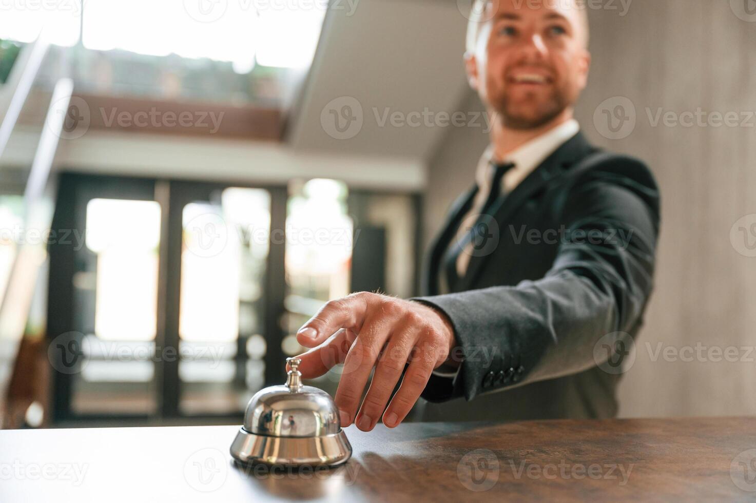 Standing, using hotel ,desk bell. A man in a black jacket at the hotel reception photo