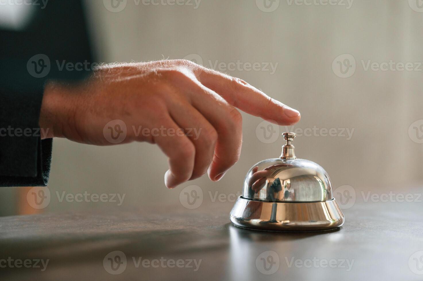 Close ,up view, using hotel desk bell. A man in a black jacket at the hotel reception photo