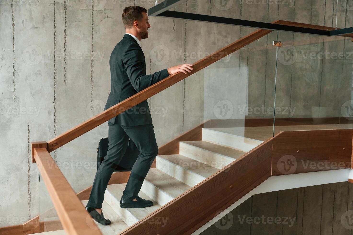 With ,case, in hands. Man in business suit and tie is on the stairs photo