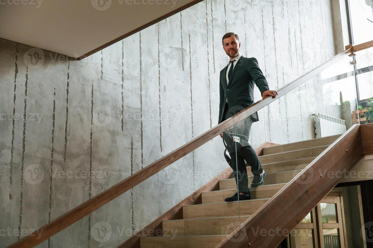 With case in, hands. Man in business suit and tie is on the stairs photo