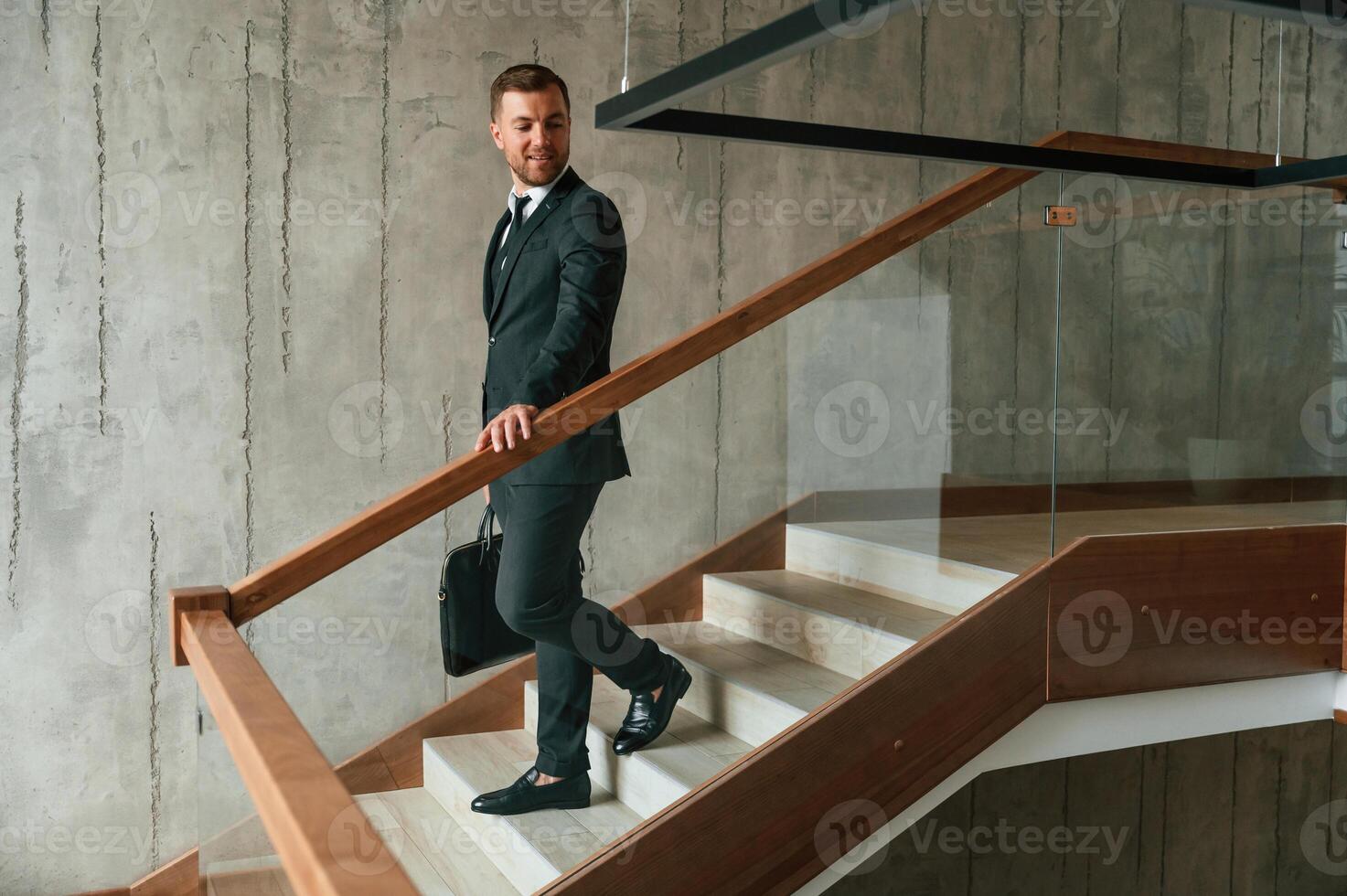 With ,case in hands. Man in business suit and tie is on the stairs photo