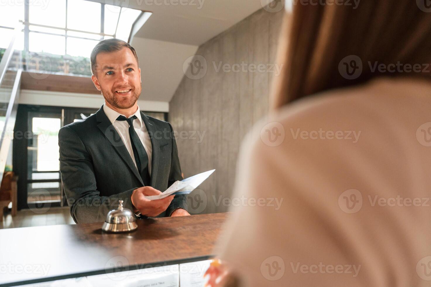 Woman, serves a visitor. A man in a black jacket at the hotel reception photo
