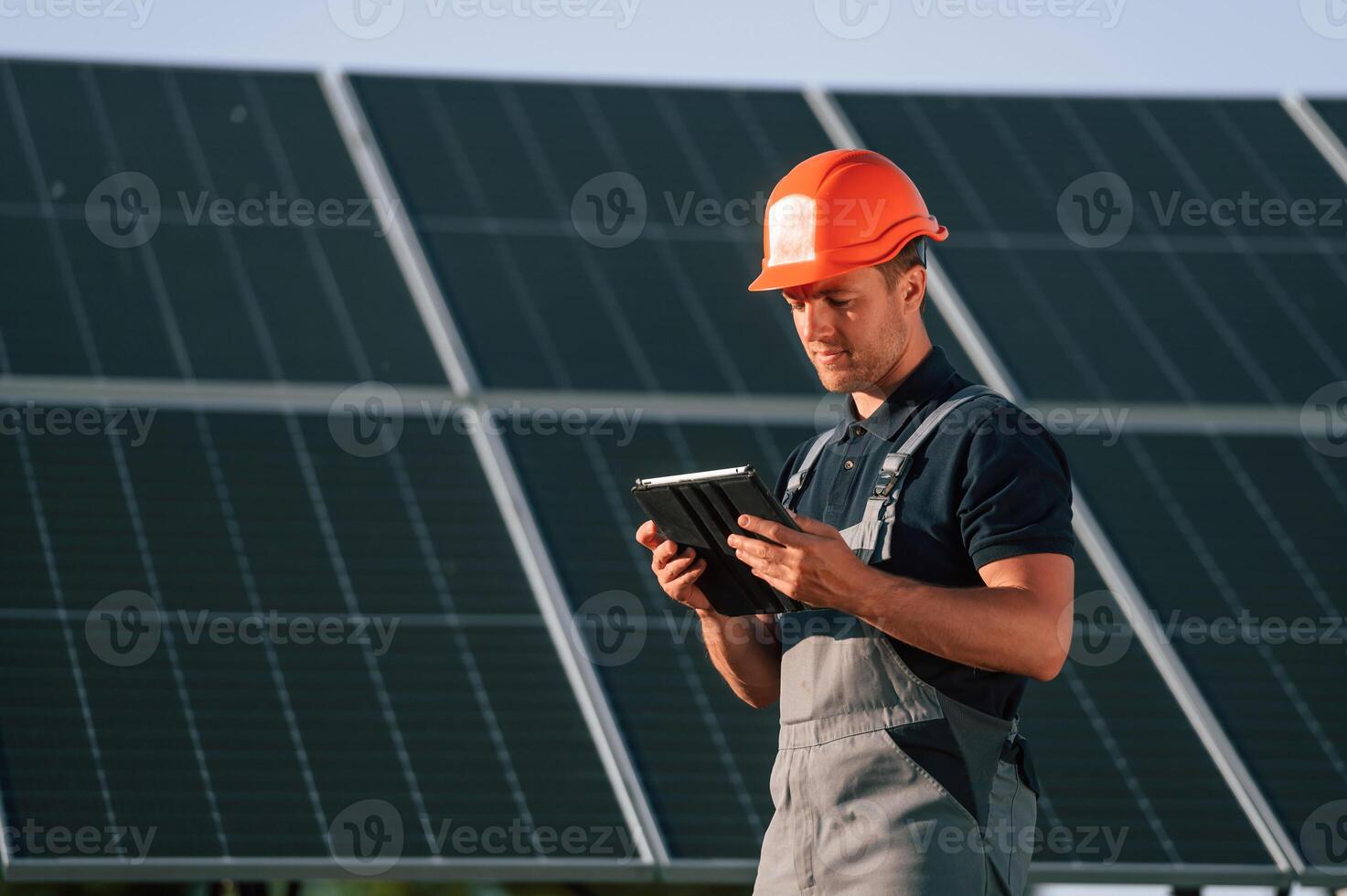 Tablet in hands. Man is doing operating and maintenance in solar power plant, photo