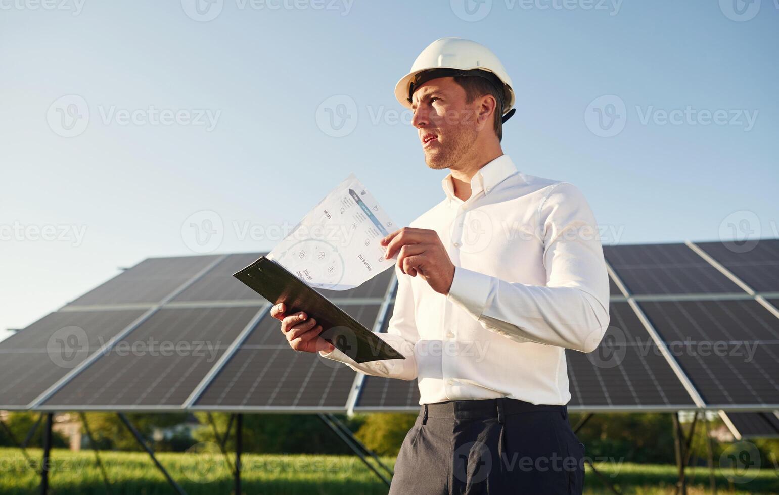 Notepad with document is in hands. Man is doing operating and maintenance in solar power plant photo