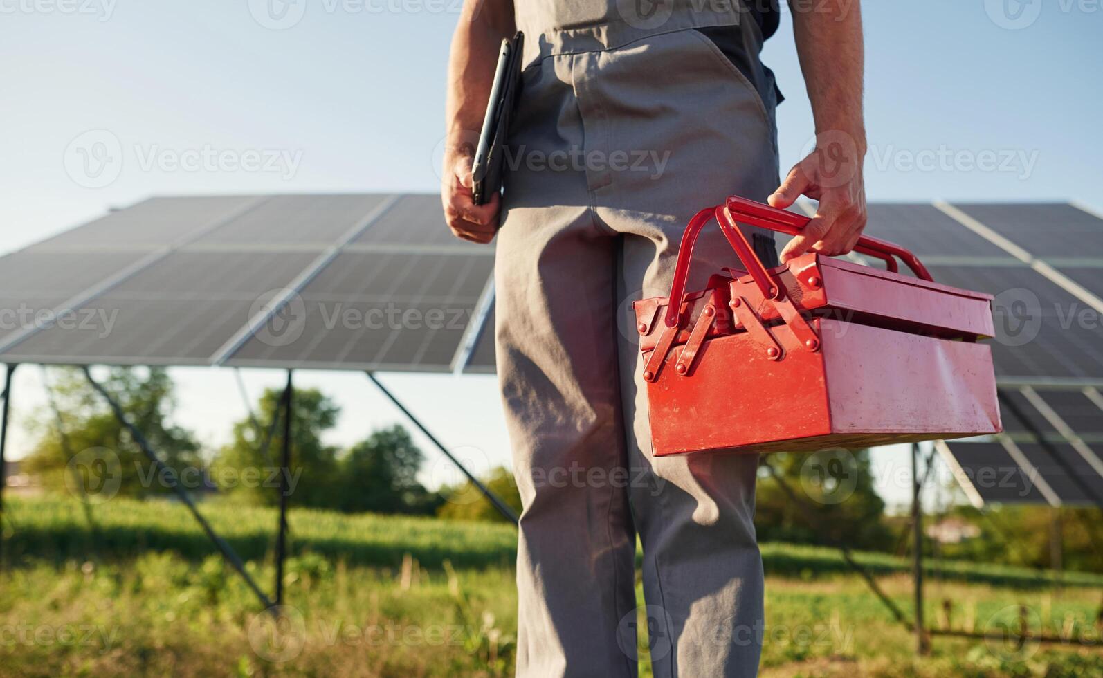 Walking ,and holding, repair toolbox. Close up view of man that is doing maintenance in solar power plant photo