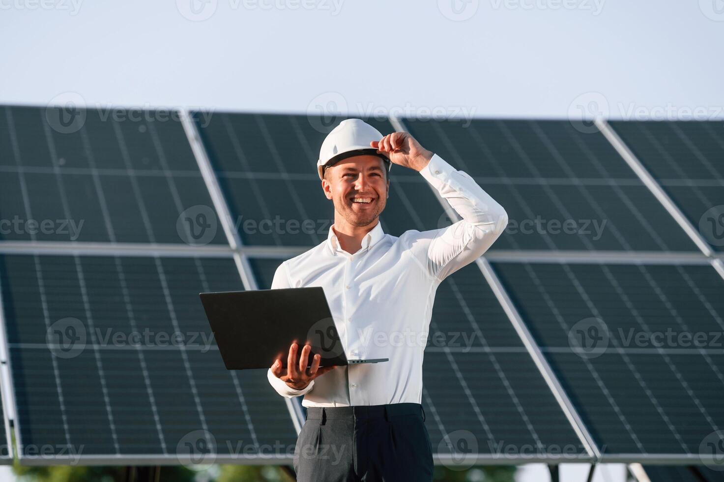 Front ,view, holding laptop. Man, is doing operating and maintenance in solar power plant photo