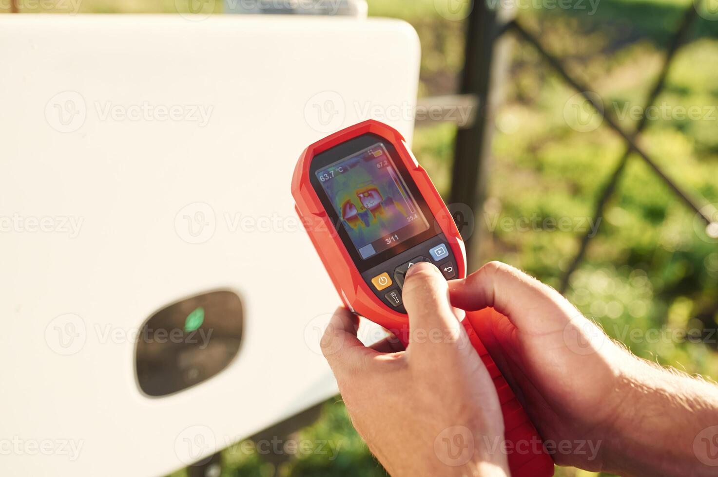 Holds a, thermal imager. Close up view of man that is doing operating and maintenance in solar power plant photo