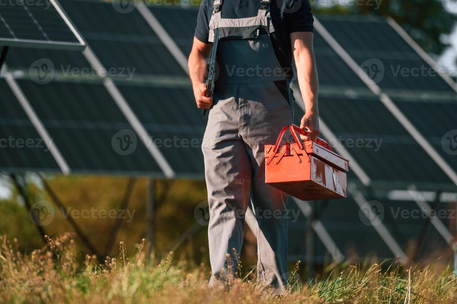 Walking ,and holding repair toolbox. Close up view of man that is doing maintenance in solar power plant photo