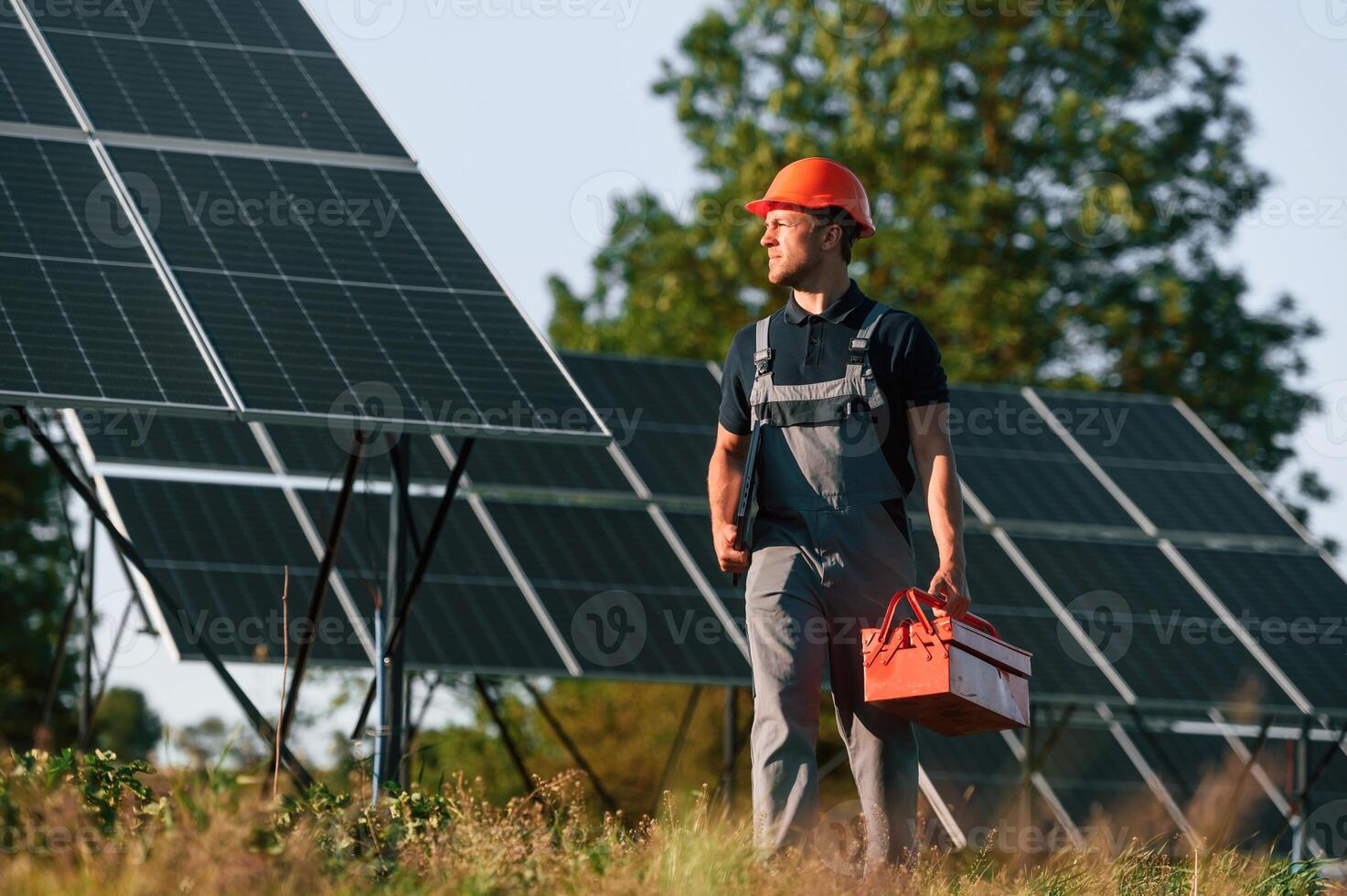 Red ,repair toolbox is in hands. Man is doing operating and maintenance in solar power plant photo