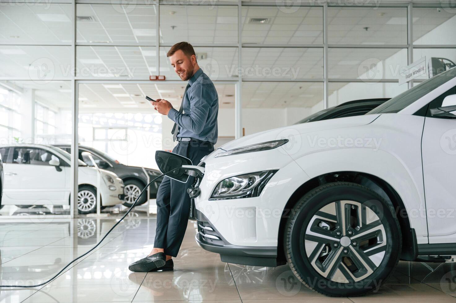 Handsome car dealership ,worker is with, electric vehicle photo