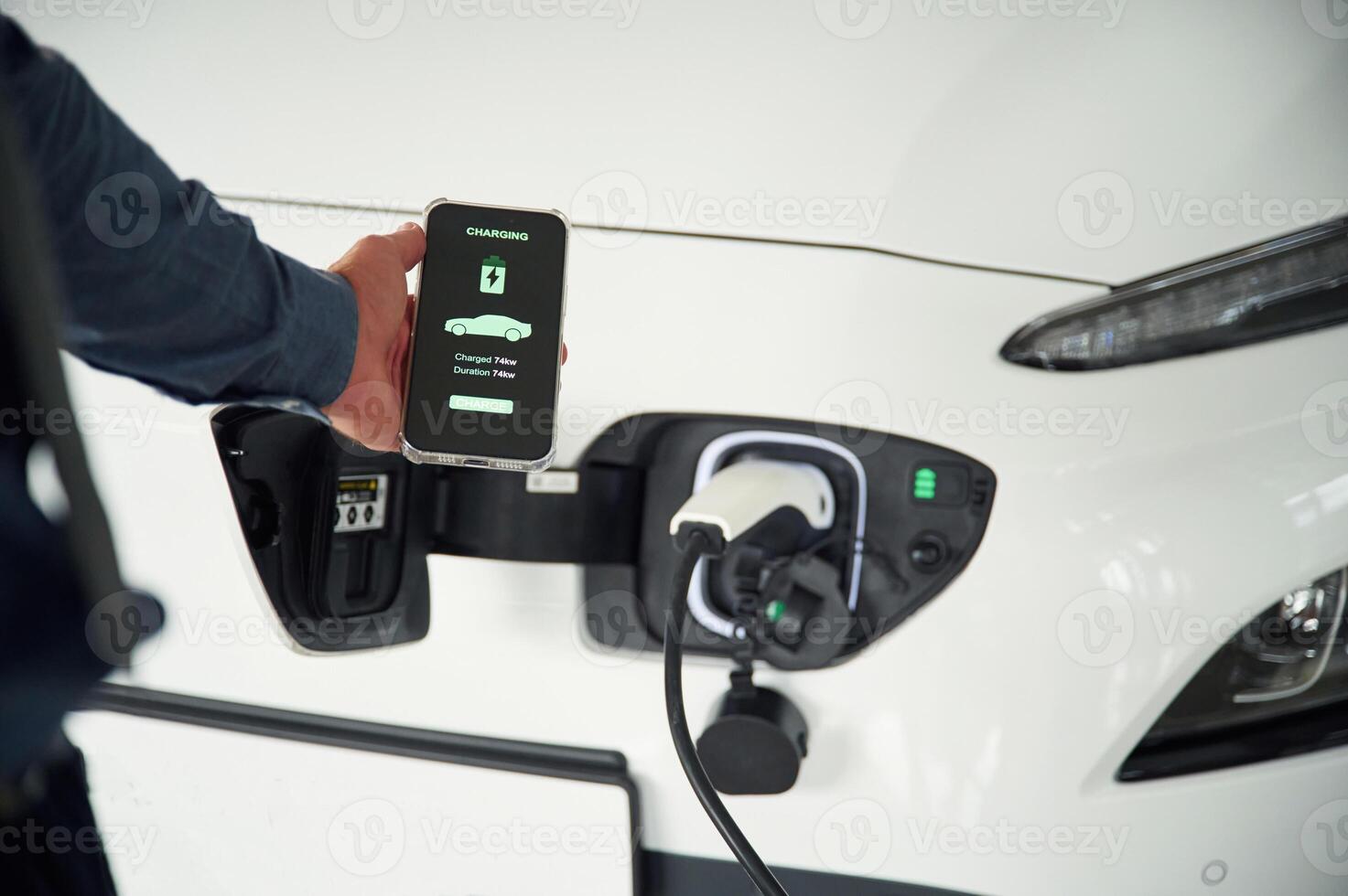 Charging process on the smartphone ,app. Close up view of man that is with electrical car photo